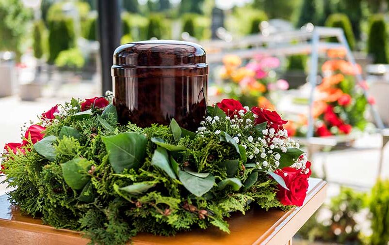 Vemos uma urna e coroa de flores. Tem curiosidades sobre cremação? Nós te explicamos 7. Confira!