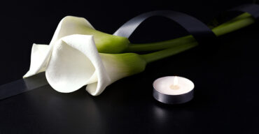 Uma flor branca num fundo preto representa as facilidades funerárias em tempo de pandemia